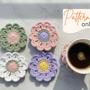 Puede incluir: Un conjunto de posavasos de flores de ganchillo hechos a mano en varios colores pastel, incluyendo verde, rosa, blanco y morado. Una taza blanca llena de café descansa sobre uno de los posavasos. El texto "Pattern only" está incluido.