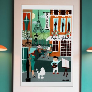 A large format framed wall art print of Paris by Mid-Century Maude. Features a French poodle, the Eiffel tower, and a cafe.  It is framed and mounted on the wall of a retro coffee shop