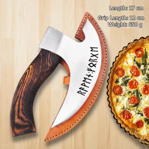 May include: A handcrafted axe with a wooden handle and a stainless steel blade. The blade is inscribed with runes and is housed in a leather sheath. The axe is 17 cm long, with a grip length of 12 cm, and weighs 650 g.