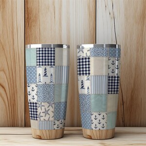 Puede incluir: Dos vasos aislados de acero inoxidable con un dise&ntilde;o de patchwork. El patchwork presenta varios patrones azules, incluyendo anclas, faros y estrellas de mar. La parte inferior de los vasos tiene un aspecto de vetas de madera.
