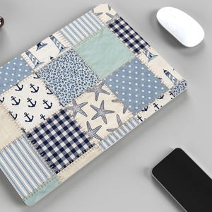Puede incluir: Alfombrilla de rat&oacute;n con dise&ntilde;o de patchwork de tem&aacute;tica n&aacute;utica. El dise&ntilde;o presenta anclas, faros, estrellas de mar, lunares y rayas en tonos azules, blancos y beige. Tambi&eacute;n se ve un rat&oacute;n inal&aacute;mbrico blanco y un smartphone.