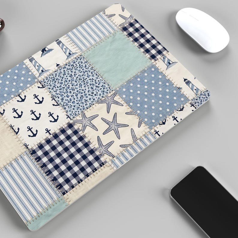 Puede incluir: Alfombrilla de rat&oacute;n con dise&ntilde;o de patchwork de tem&aacute;tica n&aacute;utica. El dise&ntilde;o presenta anclas, faros, estrellas de mar, lunares y rayas en tonos azules, blancos y beige. Tambi&eacute;n se ve un rat&oacute;n inal&aacute;mbrico blanco y un smartphone.