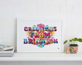 May include: A white framed print with a colorful, stylized text design that reads "Greetings from Brighton".