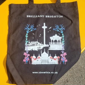 May include: Black tote bag with white text that says "BRILLIANT BRIGHTON" and a white silhouette of the Brighton Palace Pier and other landmarks. The text "www.idrewthis.co.uk" is printed at the bottom of the bag.