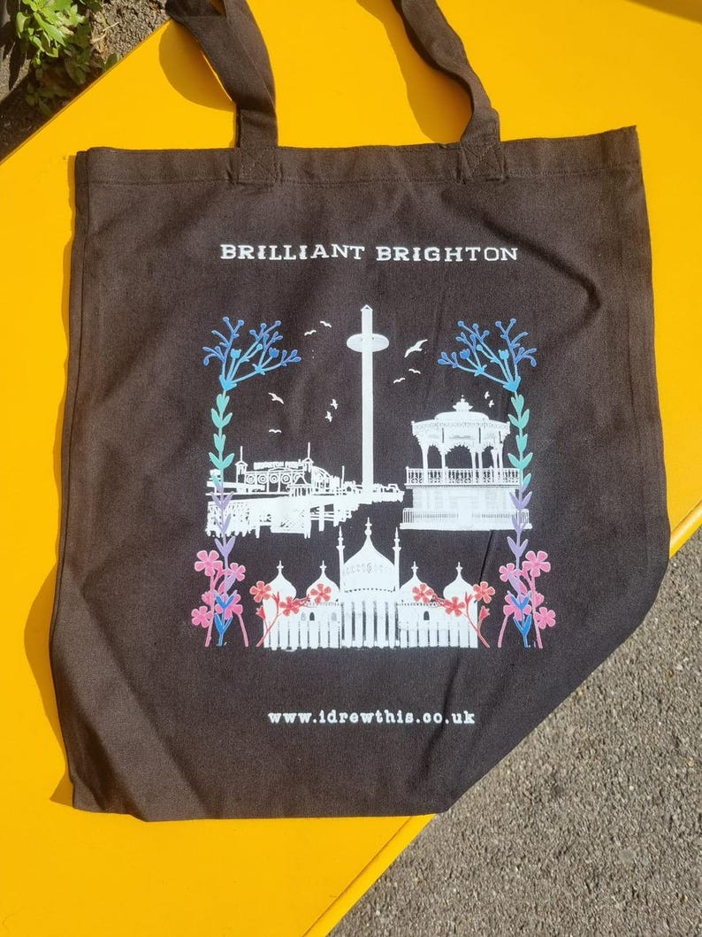 May include: Black tote bag with white text that says "BRILLIANT BRIGHTON" and a white silhouette of the Brighton Palace Pier and other landmarks. The text "www.idrewthis.co.uk" is printed at the bottom of the bag.