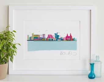 May include: A framed art print featuring a colorful skyline illustration. The artwork depicts a city skyline with buildings in shades of pink, blue, yellow, and green, set against a light blue background. The print is in a white frame.