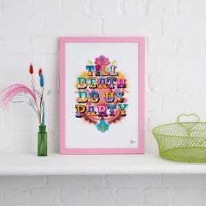 Op de afbeelding: Een roze ingelijste print met de tekst "Till Death Do Us Party" in kleurrijke, gestileerde letters. De letters zijn in een cirkelvormige opstelling met een roze en witte achtergrond.