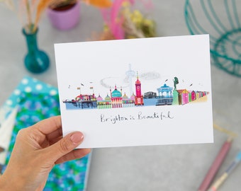 May include: A white card with a colourful illustration of Brighton pier and the text "Brighton is Beautiful".