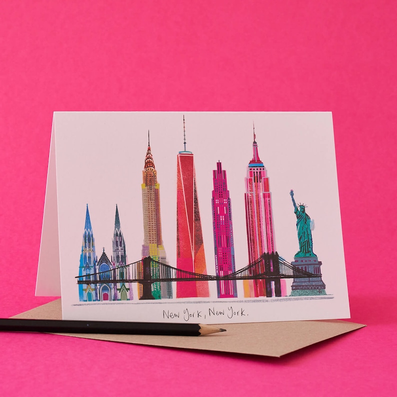Puede incluir: Una tarjeta blanca con una ilustraci&oacute;n colorida del horizonte de la ciudad de Nueva York, que incluye el Empire State Building, el Chrysler Building, la Freedom Tower y la Estatua de la Libertad. La tarjeta tiene el texto "New York, New York." impreso debajo de la ilustraci&oacute;n.