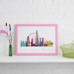 May include: A pink framed print of a colorful London skyline with the London Eye, Big Ben, and the Shard. The print is signed "Woolf" in the bottom right corner.