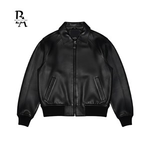 May include: A black leather jacket with a collared neckline and a zipper closure. The jacket features two front pockets and ribbed cuffs and hem. The brand logo "BELTED ATTIRE" is in the top left corner.