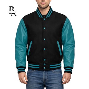 May include: Black varsity jacket with teal leather sleeves, teal accents, and a button-up front. The jacket has a ribbed collar, cuffs, and hem with teal and black stripes. The jacket has two front pockets and the brand logo "BELTED ATTIRE" in the upper left corner.