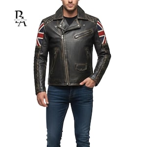 May include: A distressed black leather jacket with a Union Jack flag design on the shoulders. The jacket features a quilted design on the sleeves and shoulders, a zipper closure, and a notched collar. The jacket has the text "BELTED ATTIRE" on the upper left.