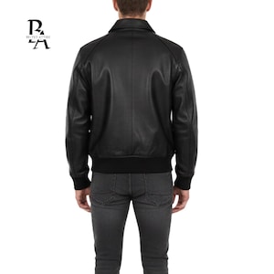 May include: Black leather jacket with a classic collar, ribbed cuffs, and a ribbed hem. The jacket has a simple, streamlined design. The logo "BELTED ATTIRE" is in the upper left corner.