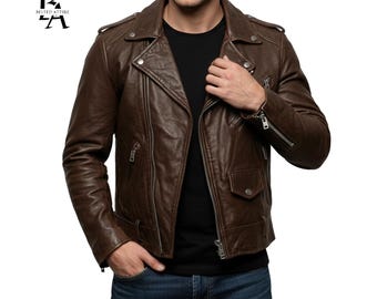 Puede incluir: Chaqueta de cuero marrón con estilo motero, con cuello de solapa y cremallera asimétrica. La chaqueta tiene múltiples bolsillos y herrajes plateados. El modelo lleva una camiseta negra y vaqueros azules. La chaqueta es de cuero.