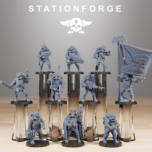 以下が含まれることがあります： グレーのミニチュア兵士のフィギュアのコレクション。一部は武器と旗を持っています。フィギュアは透明なガラスのスタンドに立っています。「STATIONFORGE」の文字とスカルのロゴが上部にあります。