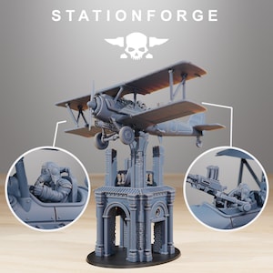 May include: A gray biplane model with intricate details, mounted on a decorative structure. The model features a pilot figure and a machine gun. The text "STATIONFORGE" is at the top of the image.