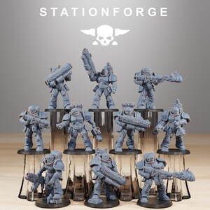 Puede incluir: Una colección de figuras en miniatura grises de soldados blindados, cada uno sosteniendo un arma. Las figuras están dispuestas sobre bases circulares negras. El texto "STATIONFORGE" está en la parte superior de la imagen, junto con un logotipo de calavera y alas.