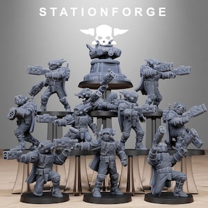 Puede incluir: Colección de figuras en miniatura grises de soldados futuristas, cada uno con un arma y una armadura detallada. Las figuras están dispuestas sobre un expositor, con el texto "STATIONFORGE" y un logotipo de calavera en la parte superior.
