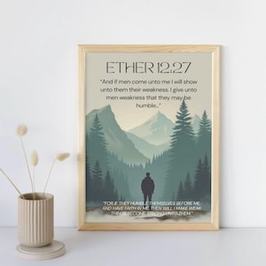 May include: A framed print with the text "ETHER 12:27" and a quote about humility. The artwork features a silhouette of a person in front of a mountain landscape in shades of green and gray. A beige vase with dried flowers is on the left.
