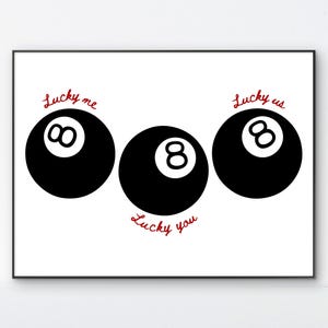 Pode incluir: Impress&atilde;o emoldurada com tr&ecirc;s bolas de bilhar pretas sobre fundo branco. As palavras "Lucky me", "Lucky us" e "Lucky you" est&atilde;o escritas em vermelho acima e abaixo das bolas. Design gr&aacute;fico simples.