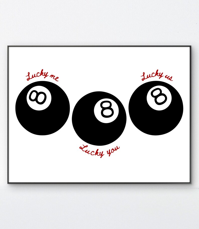 Pode incluir: Impress&atilde;o emoldurada com tr&ecirc;s bolas de bilhar pretas sobre fundo branco. As palavras "Lucky me", "Lucky us" e "Lucky you" est&atilde;o escritas em vermelho acima e abaixo das bolas. Design gr&aacute;fico simples.