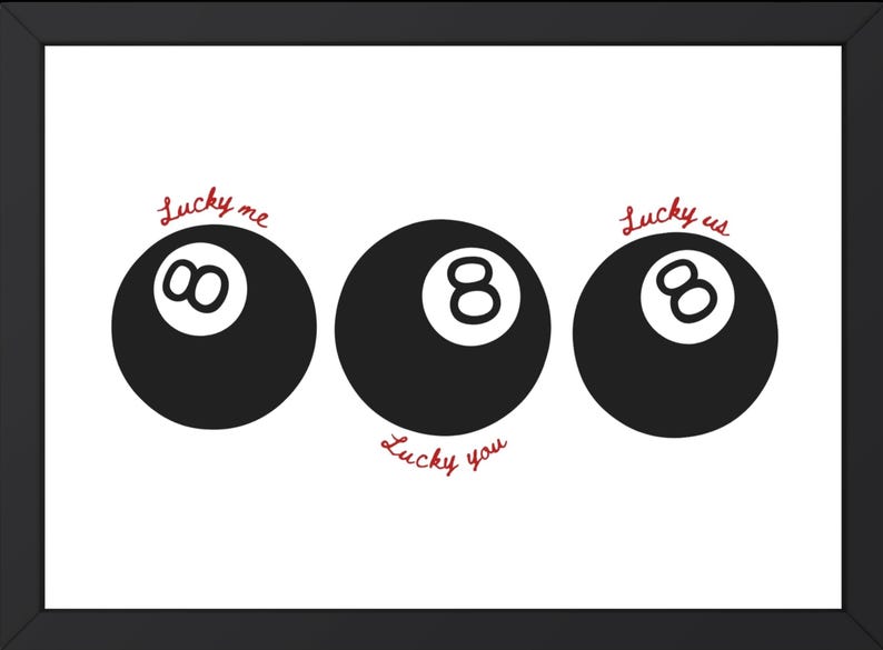 Pode incluir: Impress&atilde;o emoldurada com tr&ecirc;s bolas de bilhar pretas sobre um fundo branco. Os textos "Lucky me", "Lucky you" e "Lucky us" est&atilde;o escritos em it&aacute;lico vermelho acima e abaixo das bolas. A moldura &eacute; preta.