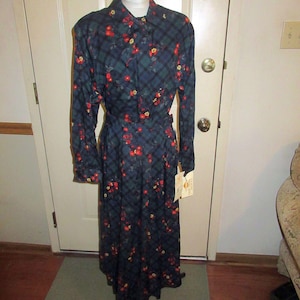 May include: A long-sleeved dress with a plaid and floral print in shades of blue, red, and yellow. The dress has a collared neckline and a tie at the neck. The dress has a tag that says "Golden Classics".