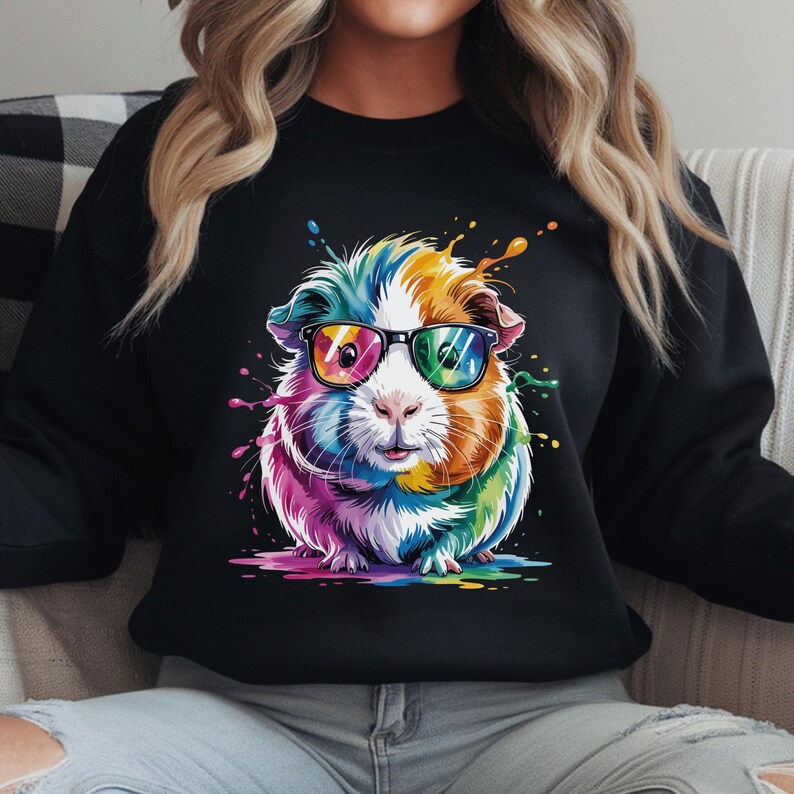 May include: Black sweatshirt featuring a colorful guinea pig wearing sunglasses. The guinea pig is depicted with vibrant rainbow hues and paint splatter effects. The design is centered on the front of the sweatshirt.