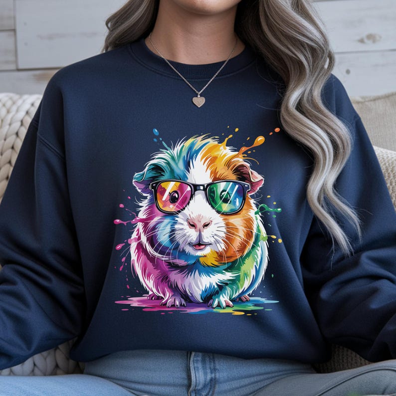 May include: Navy blue sweatshirt featuring a colorful guinea pig wearing sunglasses. The guinea pig has rainbow-colored fur and is surrounded by paint splatters. The design is a vibrant, eye-catching graphic.