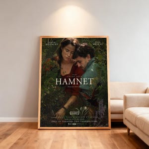 Puede incluir: Un póster enmarcado de la película "Hamnet" con Jessie Buckley y Paul Mescal. El póster tiene un marco de madera y muestra el título y los créditos de la película. La imagen muestra a dos personas abrazándose en un jardín, con el texto "Only in Theaters This Thanksgiving."