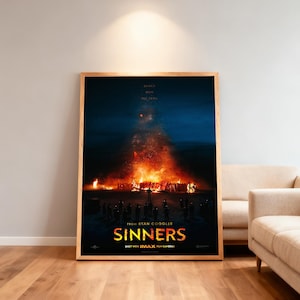 Puede incluir: Un póster de película enmarcado con una combinación de colores azul oscuro y naranja. El póster presenta una gran hoguera con figuras silueteadas y el título "SINNERS" en letras amarillas. También es visible el texto "SHOT WITH IMAX FILM CAMERAS".