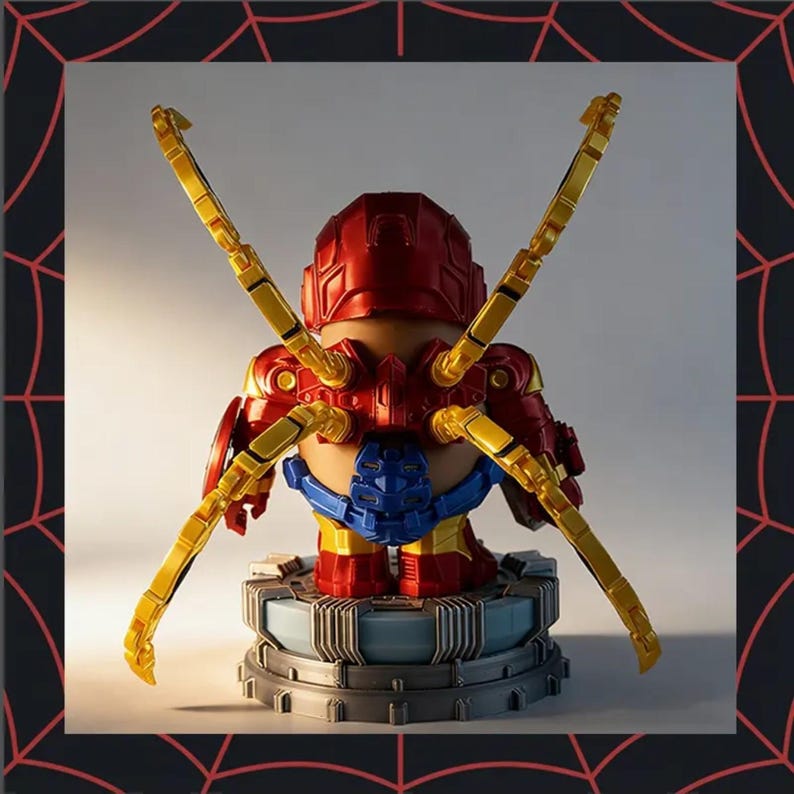 May include: A red and gold action figure with yellow mechanical arms, standing on a gray and blue platform. The figure has a red helmet and armor, with blue accents. The arms extend outward, creating a dynamic pose.