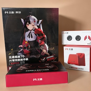Puede incluir: Una colección de accesorios de juego que incluye una caja negra grande con un personaje de anime, una caja roja y blanca para una base de carga, una caja blanca pequeña con piezas de mando y una caja roja rectangular con el logo de Betop.