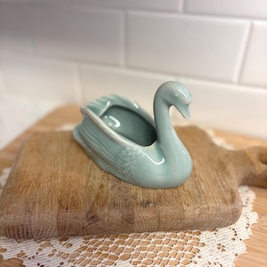 May include: A set of three ceramic nesting bowls in shades of blue, green, and white. The bowls feature a speckled glaze and a simple, modern design. The largest bowl measures approximately 6 inches in diameter.