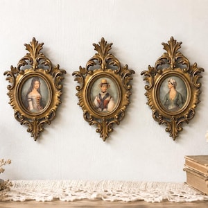 May include: Three antique gold-colored oval frames with portraits of people in period clothing. The frames are ornate, with detailed scrollwork. The portraits are in muted colors, and the overall aesthetic is vintage and elegant.