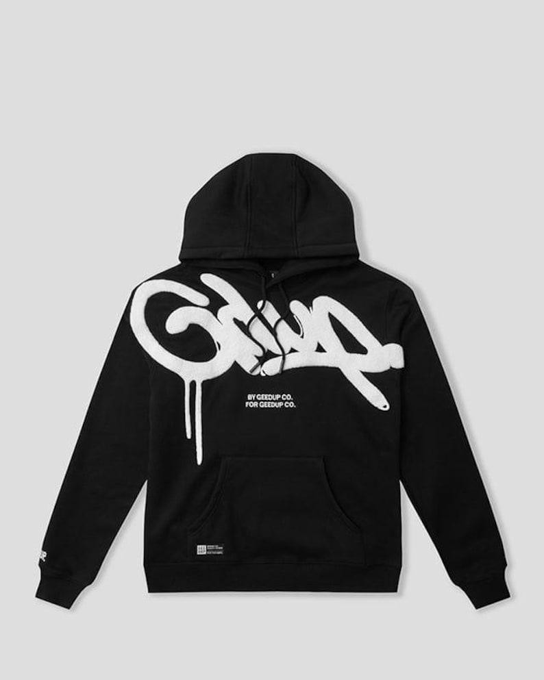 May include: Black hooded sweatshirt with a white graffiti-style design on the front. The design includes the word "Grip" in a stylized font with dripping paint effects. The text "BY GEEDUP CO. FOR GEEDUP CO." is below the main design.