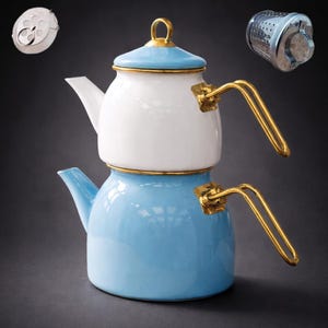 May include: A two-tiered, blue and white enamel teapot with gold-colored handles and trim. The teapot has a lid with a gold handle. Two metal tea infusers are also shown.
