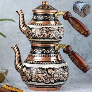 May include: A copper and black tea kettle with floral and geometric patterns. The kettle has a wooden handle and a matching lid. A metal tea infuser is also included.