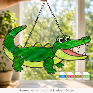 Può includere: Un acchiappasole in vetro colorato a forma di alligatore con pannelli di vetro testurizzato verde brillante e verde chiaro, linee di saldatura in metallo nero, bocca rossa e occhi bianchi. Appeso a una catena nera, include file SVG, PDF, JPG e PNG.