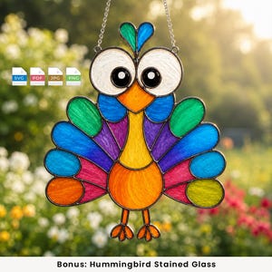 May include: A stained glass suncatcher shaped like a colourful peacock with large white eyes, a yellow neck, an orange body, and multi-coloured tail feathers in shades of green, blue, purple, and pink, suspended by a silver metal chain.