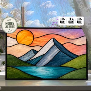 May include: Stained glass panel depicting a mountain landscape with a vibrant sunset. The artwork features a large orange sun, blue mountains, and a turquoise lake. The panel is framed in black and includes a "HOBBY LICENSE" sticker.