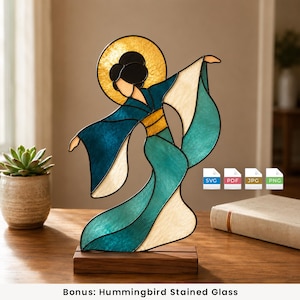 Könnte beinhalten: Ein Buntglas-Kunstwerk, das eine Figur in einem fließenden blaugrünen und weißen Gewand mit goldenem Heiligenschein auf einem rechteckigen Holzsockel zeigt. Das Design hat schwarze Bleilinien und enthält vier kleine Symbole mit SVG, PDF, JPG und PNG.