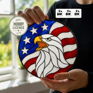 May include: A circular stained glass panel depicting the American flag and a bald eagle. The eagle has a yellow beak and white feathers, set against a blue background with white stars and red and white stripes.