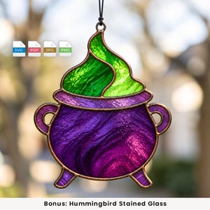 May include: A stained glass hanging ornament shaped like a cauldron with a purple base and a swirling green top, outlined in copper metal. The piece features two side handles and three small feet, suspended by a black cord for display purposes.
