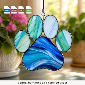May include: A stained glass paw print suncatcher featuring marbled blue, teal, and white glass panels held together by dark metal framing. The piece hangs from a black cord and includes digital file icons for SVG, PDF, JPG, and PNG formats.