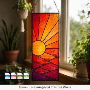 May include: A rectangular stained glass panel featuring a sunrise design with a yellow sun, orange and red rays, and purple hills at the bottom. The piece is framed in black metal and hangs from a chain. Four file format icons are visible below.