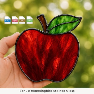 Op de afbeelding: Een glas-in-lood appel suncatcher met een getextureerd dieprood lichaam, een groen blad en een bruine steel, allemaal omlijnd met zwart metaalsoldeer. De digitale bestandsformaten SVG, PDF, JPG en PNG worden als iconen in de hoek getoond.