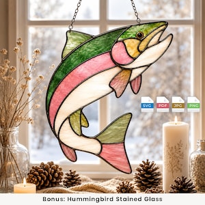May include: A stained glass suncatcher shaped like a fish with green, pink, and white glass panels held together by dark metal solder lines. The fish is suspended by a metal chain and features a small black eye detail in the yellow head section.