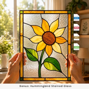 Op de afbeelding: Een rechthoekig glas-in-loodpaneel met een centrale gele zonnebloem met een getextureerd bruin hart en twee groene bladeren. De zonnebloem is geplaatst tegen een heldere, getextureerde glazen achtergrond en omlijst door een rand van amberkleurig glas.